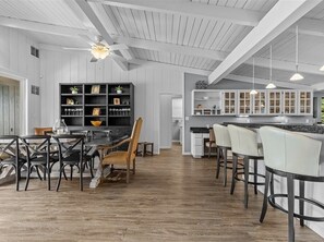 Eine geräumige Küche mit weißen Schränken, einem Essbereich mit Holztisch und -stühlen sowie einer Bar mit Sitzgelegenheiten.