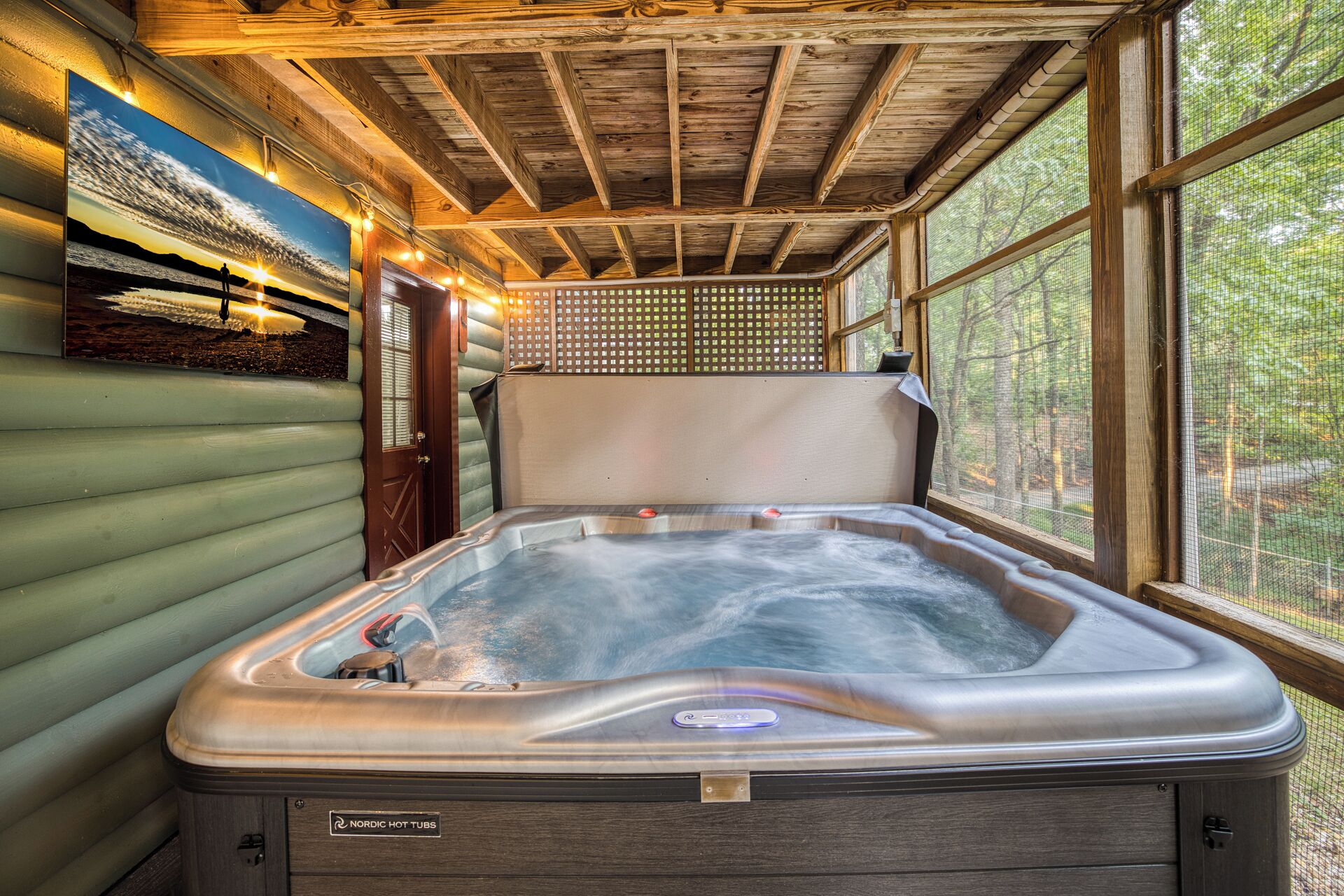A hot tub with a wooden ceiling and a view of the outdoors through large windows.