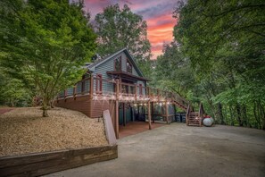 A cabin with a wooden deck, surrounded by trees, and a clear sky. - Starling Hollow • Hot Tub | Fire Pit | Family Vibe (Blue Ridge)