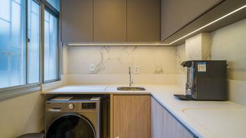 A compact kitchen with a washing machine, a sink, and a refrigerator.