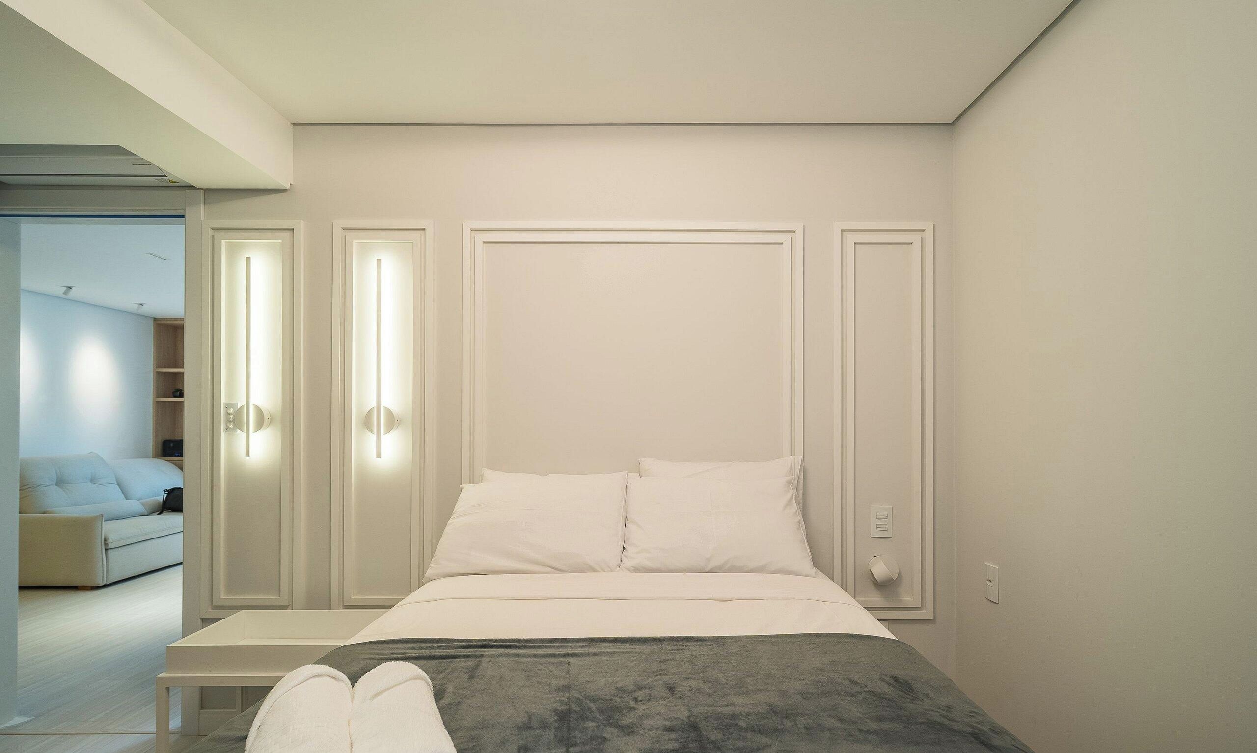 A bedroom with a bed, bedside tables, and a wardrobe.