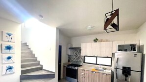 A modern kitchen with a built-in stove, microwave, and refrigerator. There is a staircase leading to another level and a dining area with a table and chairs. - 3 Bedroom House In Secure Privada (La Paz)