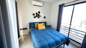 A bedroom with a large bed, a window with curtains, a wall-mounted air conditioner, and a decorative hexagonal wall piece. - 3 Bedroom House In Secure Privada (La Paz)