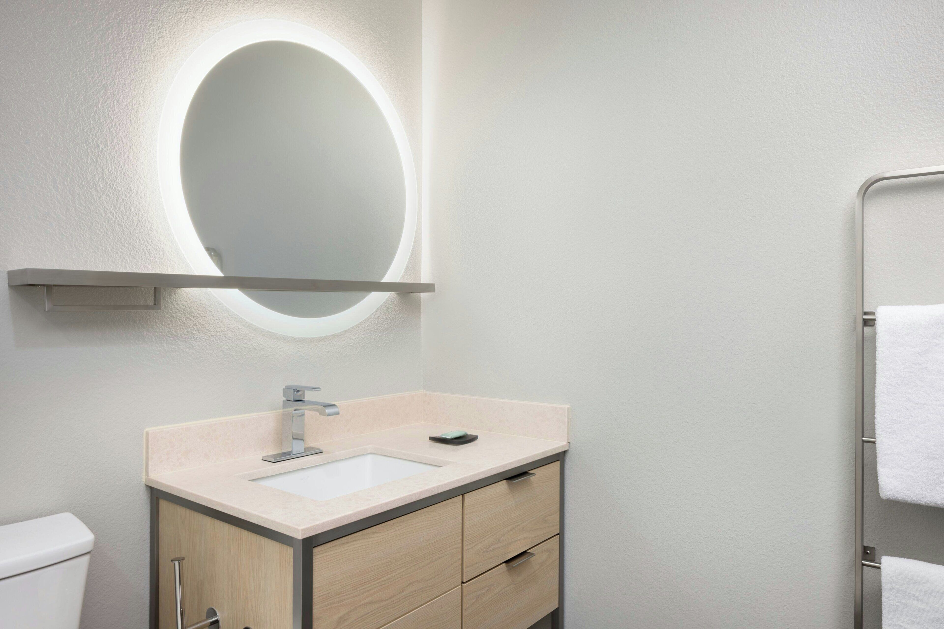 A bathroom with a sink, mirror, and towel rack.