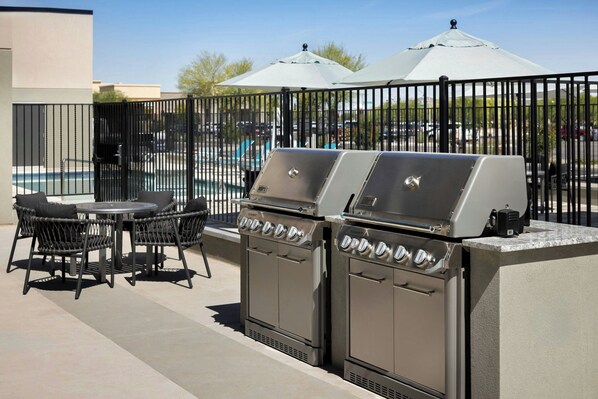 An outdoor patio with two Summit gas grills, a pool, and a covered seating area.