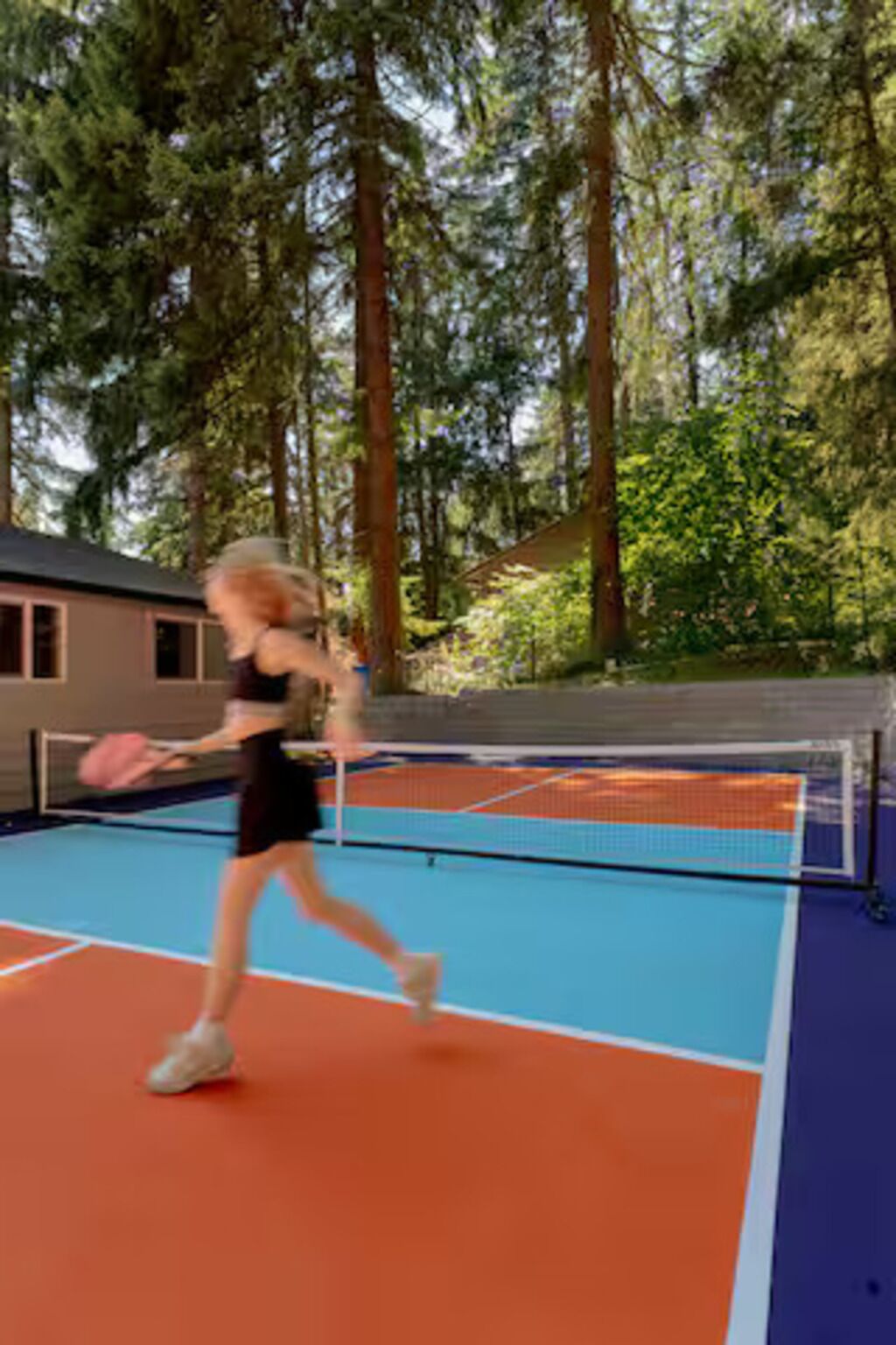 An outdoor tennis court surrounded by trees.