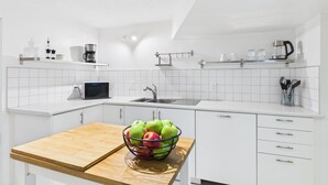 Eine moderne Küche mit weißen Schränken, einer Holzarbeitsplatte, einem Spülbecken und einer Mikrowelle.