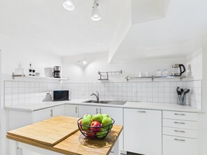 Eine moderne Küche mit weißen Schränken, einer Holzarbeitsplatte, einem Spülbecken und einer Mikrowelle.