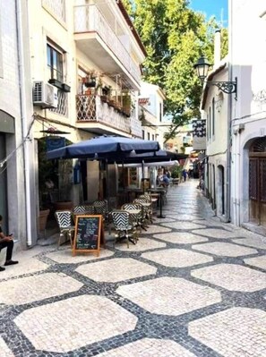 A narrow street with outdoor seating and a patterned tile floor. - Cascais By the Ocean (Cascais)
