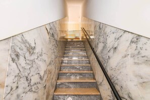 Eine Marmortreppe mit Handlauf, die zu einer Empore mit Geländer führt.