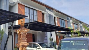 A modern two-story house with a covered porch, a brick pillar, and a parked car. - Luxury central Denpasar home with pool and clubhouse for an easy family stay. (Denpasar Barat)