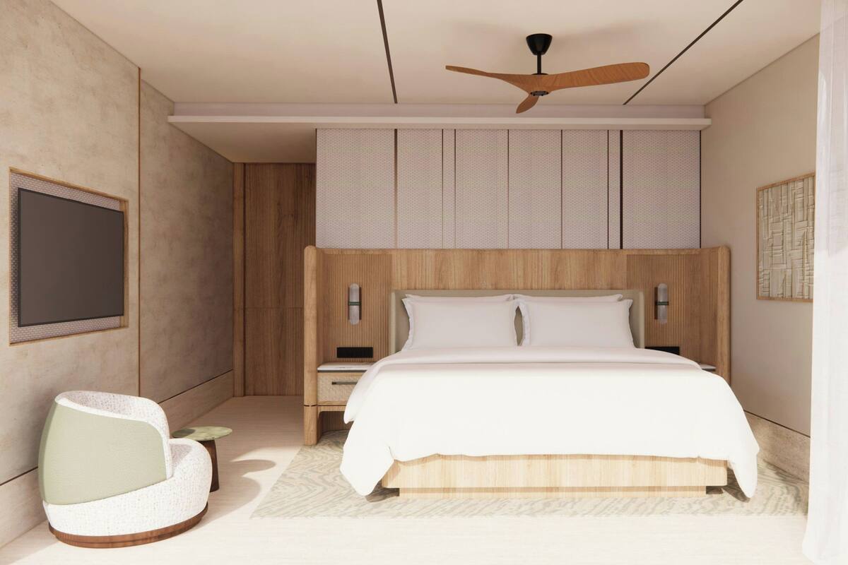 A modern bedroom with a bed, nightstands, a ceiling fan, a wall-mounted TV, and a seating area.
