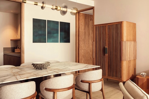 A dining area with a marble table, four upholstered chairs, a wooden cabinet, and abstract wall art.