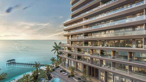 Un hotel de varios pisos con balcones, una zona de piscina y vista al océano.