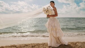 A person standing on a beach holding a bouquet of flowers, with the ocean and sky in the background. - The St. Regis Costa Mujeres Resort, Cancun (Cancun)
