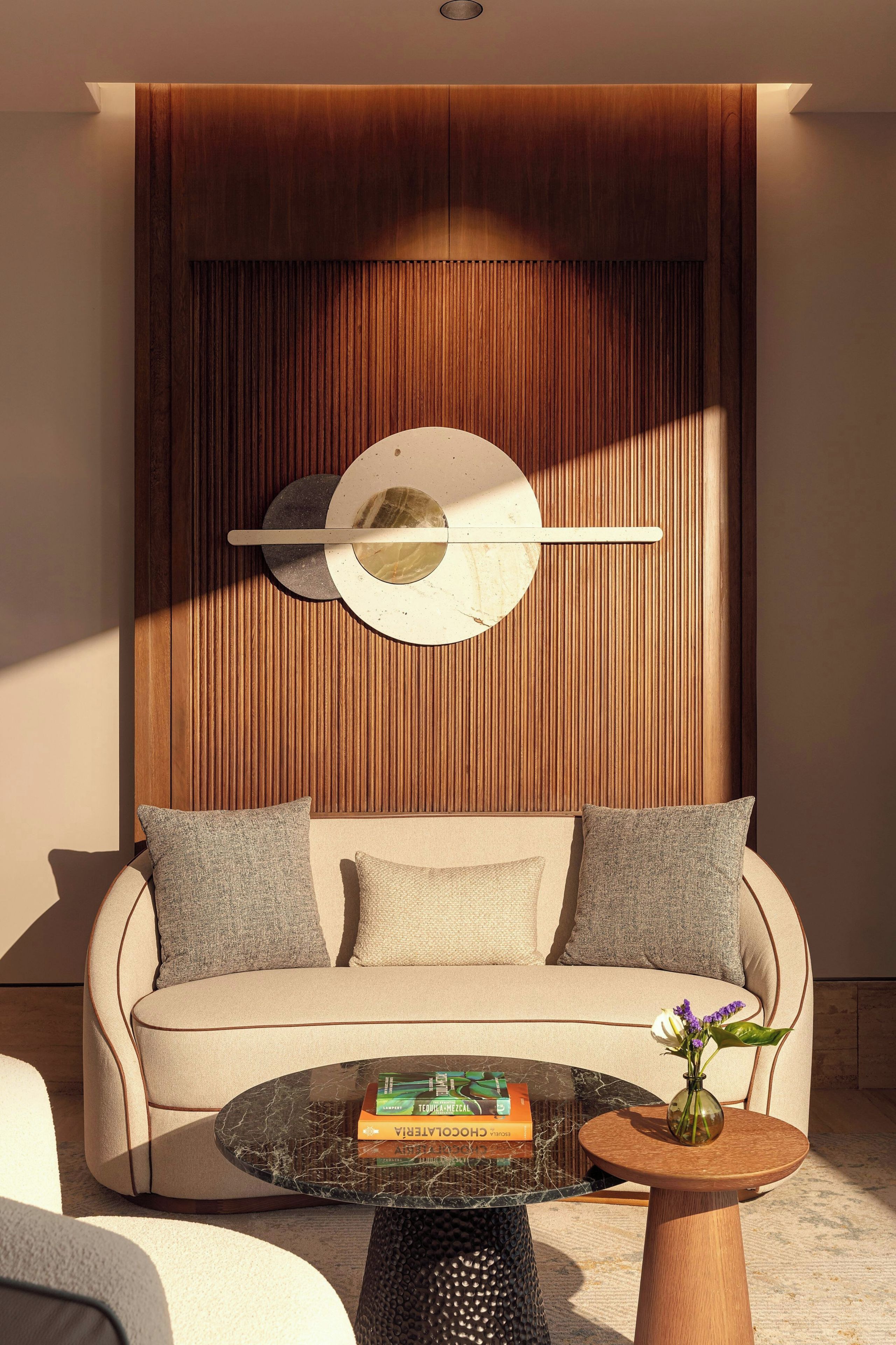 A modern living room with a sofa, a coffee table, and a decorative wall panel.