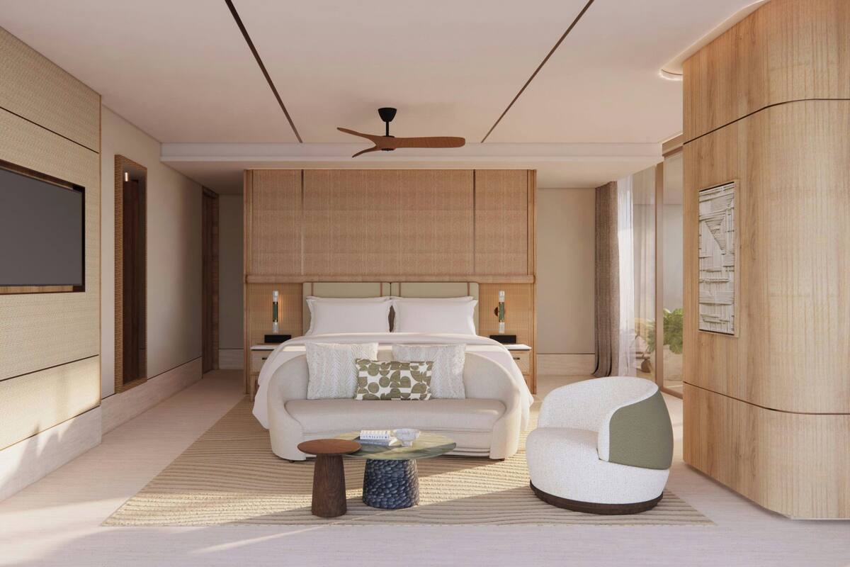 A modern bedroom with a large bed, a sofa, a chair, a small table, and a ceiling fan.