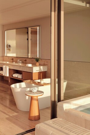 A modern bathroom with a large bathtub, a vanity with a mirror, and a small wooden side table. - The St. Regis Costa Mujeres Resort, Cancun (Cancun)