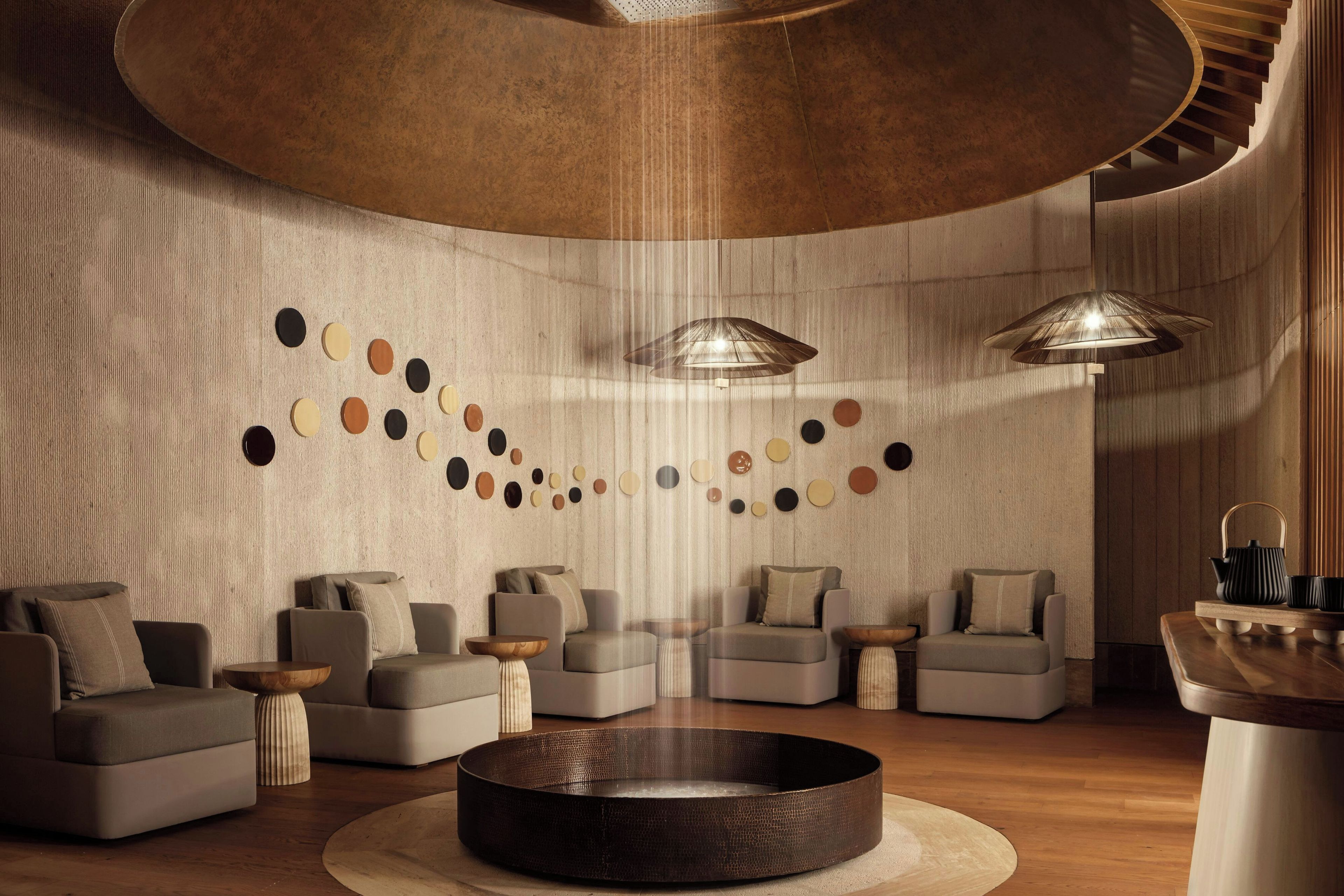 A modern lounge area with sofas, a central coffee table, and pendant lighting.