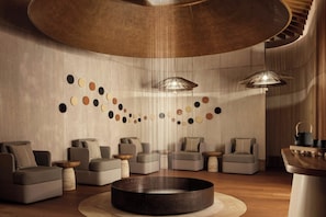 A modern lounge area with sofas, a central coffee table, and pendant lighting.