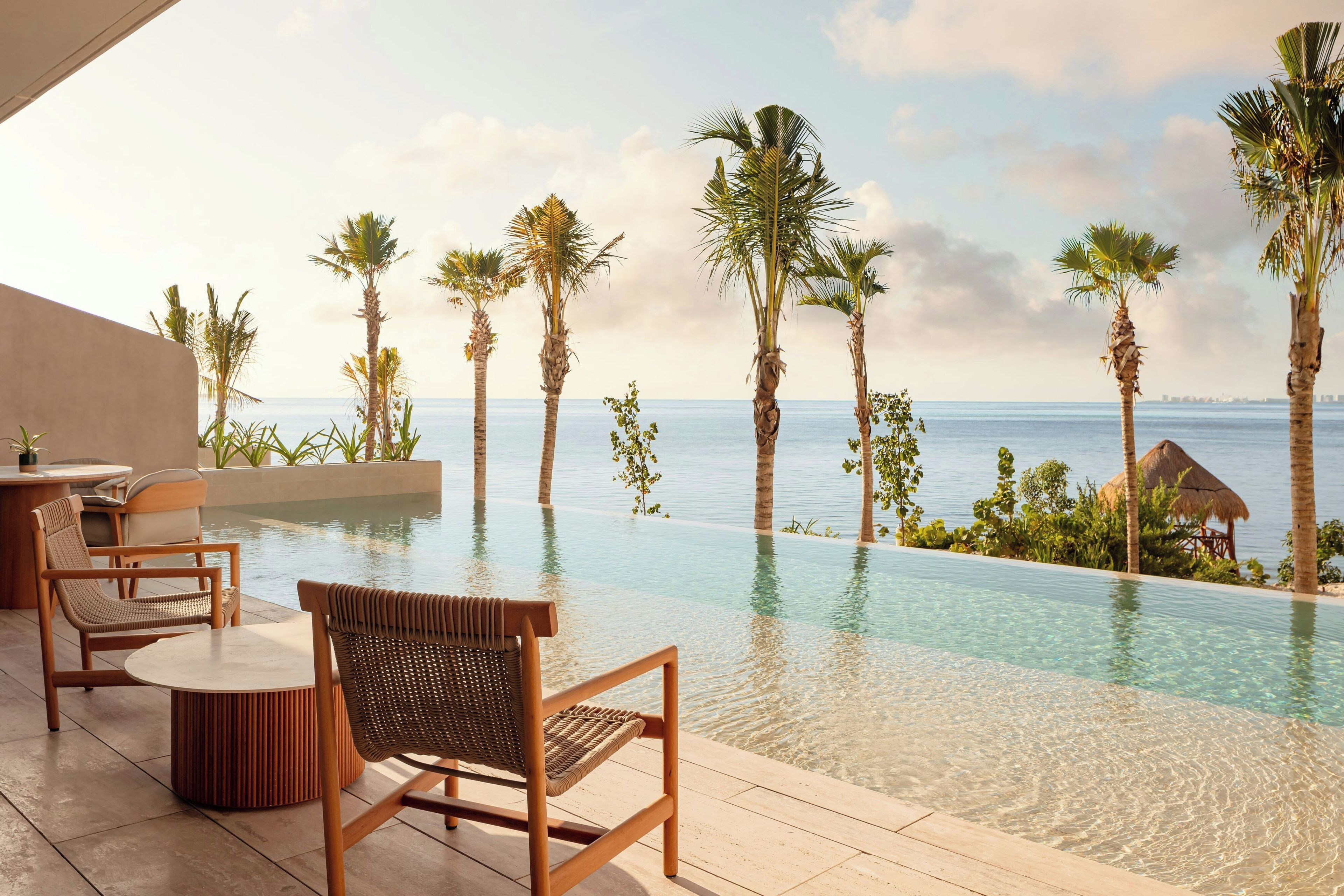 Un área junto a la piscina con sillones de descanso y vista al mar.