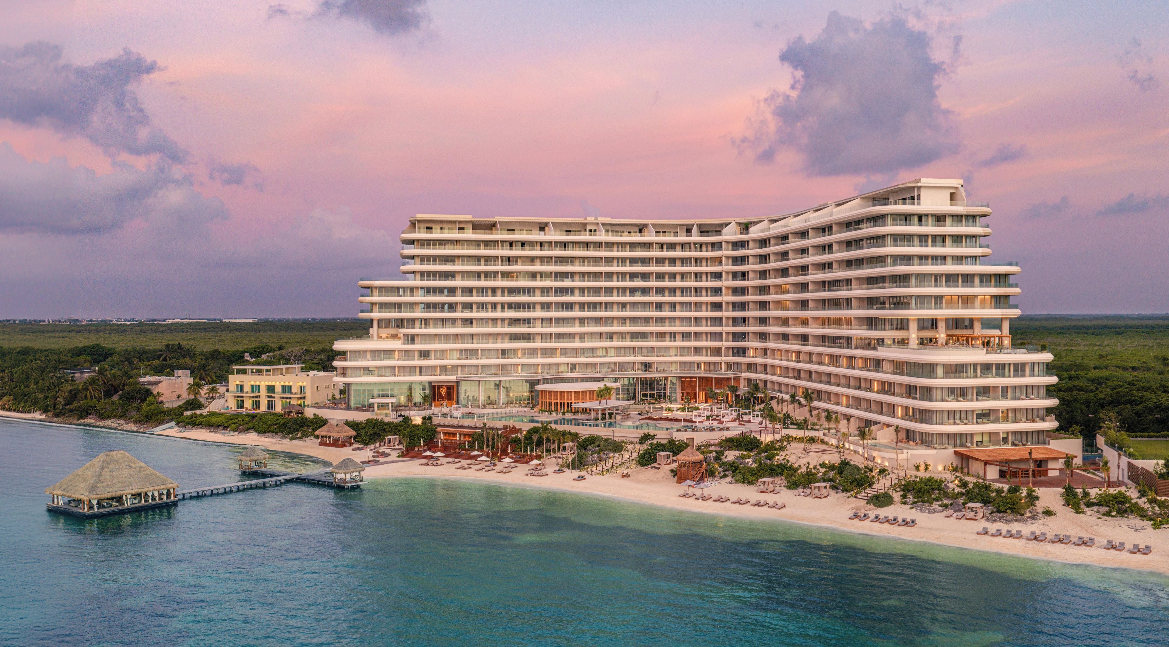 A large resort hotel with multiple floors, a pool area, and a beachside location.