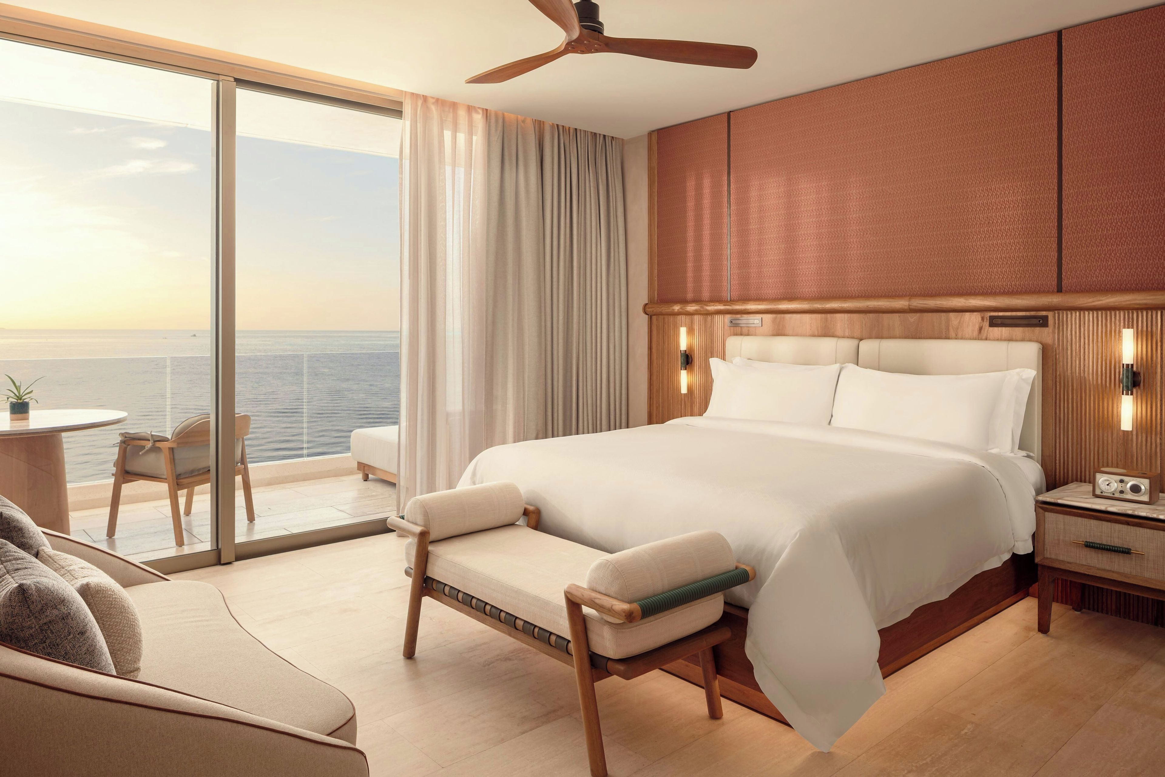 A hotel room with a large bed, a sitting area with a chair, a small table, and a view of the ocean.