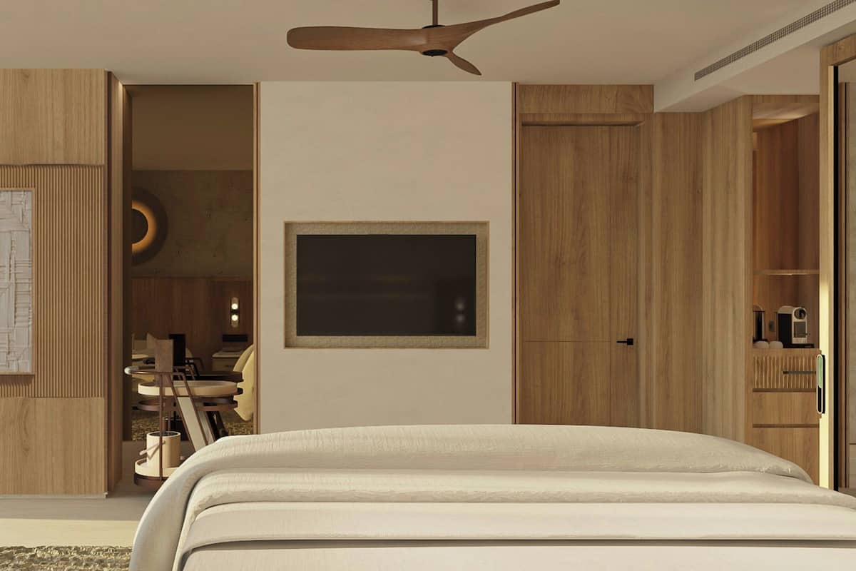 A modern bedroom with a large bed, a ceiling fan, wooden paneling, and a TV mounted on the wall.