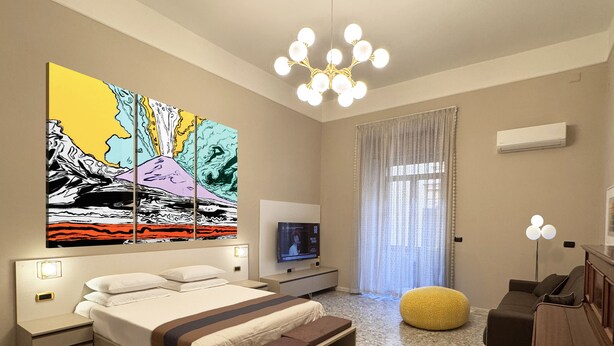 A modern hotel room with a large bed, a TV, a sofa, and a coffee table. - Your Authentic Retreat in the Heart of Naples. (Napoli)