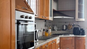 A kitchen with wooden cabinets, a stainless steel oven, a gas stove, and a microwave. - Your Authentic Retreat in the Heart of Naples. (Napoli)