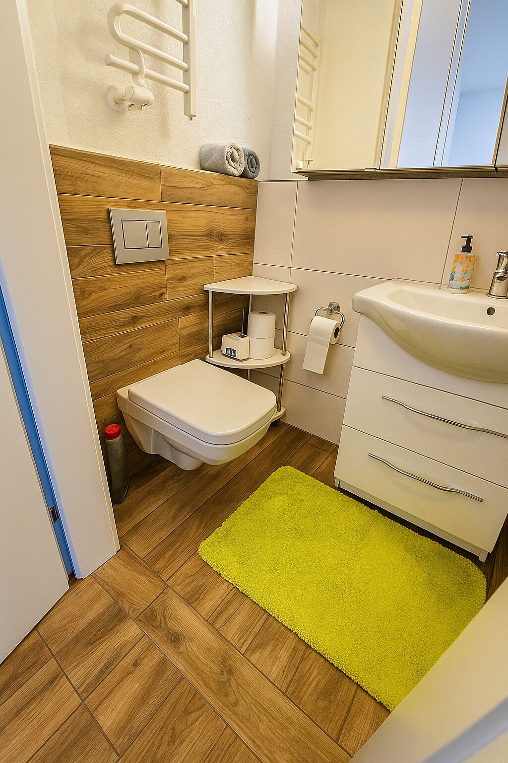 Une petite salle de bain comprenant des toilettes, un lavabo, un miroir et une petite étagère avec des articles de toilette.