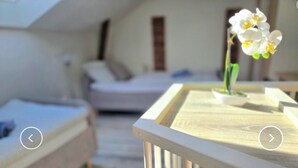 Una camera da letto con un letto, un tavolino con un fiore e vista su un'altra stanza.