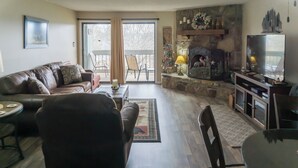 Ein Wohnzimmer mit Kamin aus Stein, einem Fernseher und einem Essbereich mit Tisch und Stühlen.