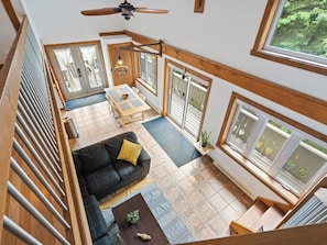 A spacious loft with a dining area, a sofa, and large windows.