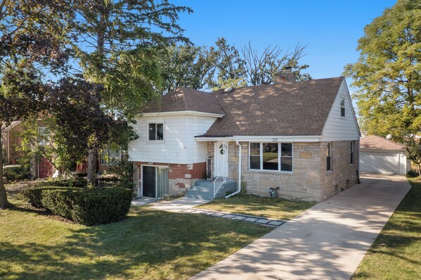 A two-story house with a front porch, a garage, and a well-maintained lawn. - Unique Home in Maywood - 5 Bedroom (Maywood)