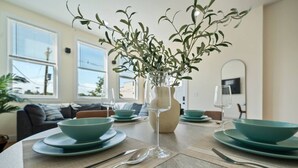 Mesa de jantar posta com tigelas azul-turquesa, um copo de vidro transparente e um vaso com folhagem verde.