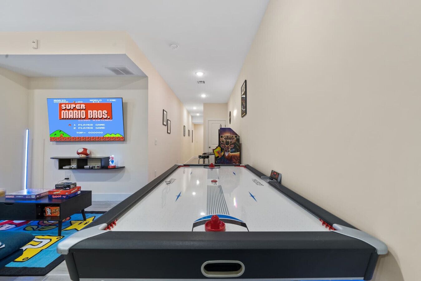 Une pièce équipée d’une table de billard, d’un écran de télévision diffusant des jeux Super Mario Bros. et d’une console de jeux.