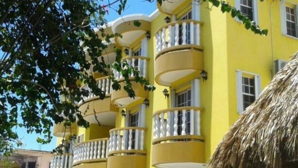 A yellow building with balconies and a thatched roof structure. - Paradise Suites & Residence  (San Pedro)