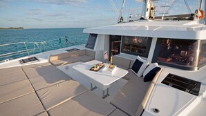 Le pont d’un yacht, avec un espace repas, des sièges confortables et une vue sur la mer.