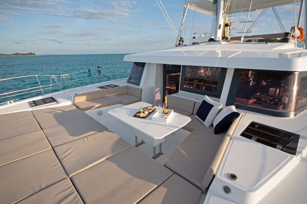 Le pont d’un yacht, avec un espace repas, des sièges confortables et une vue sur la mer.