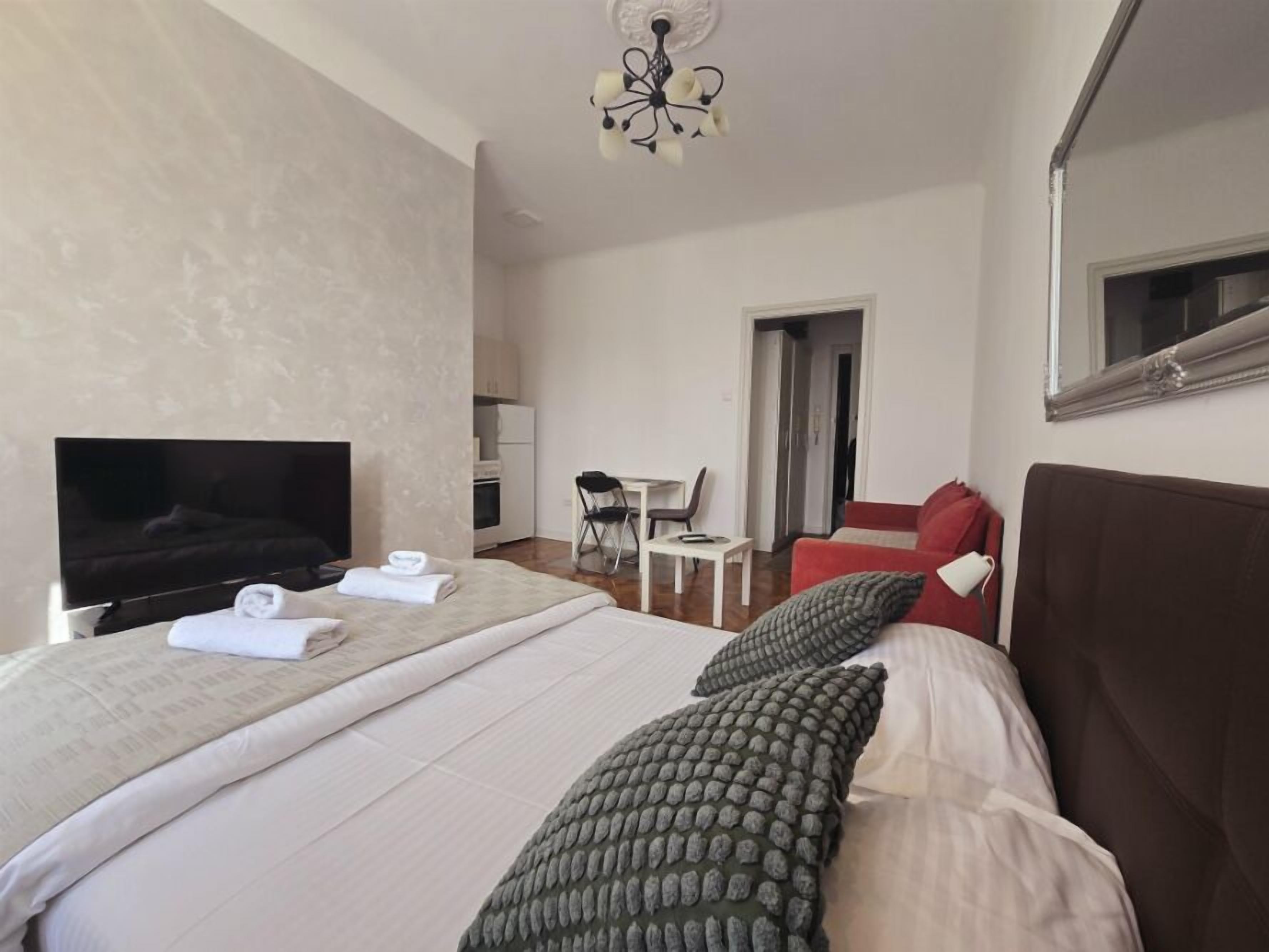 A hotel room with a large bed, a TV, a desk, and a chair.