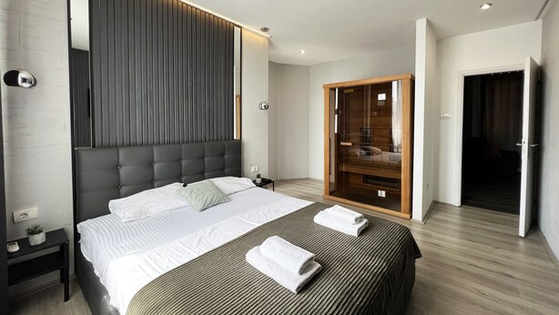 Una habitación de hotel moderna con una cama grande, un armario y una mesita de noche.