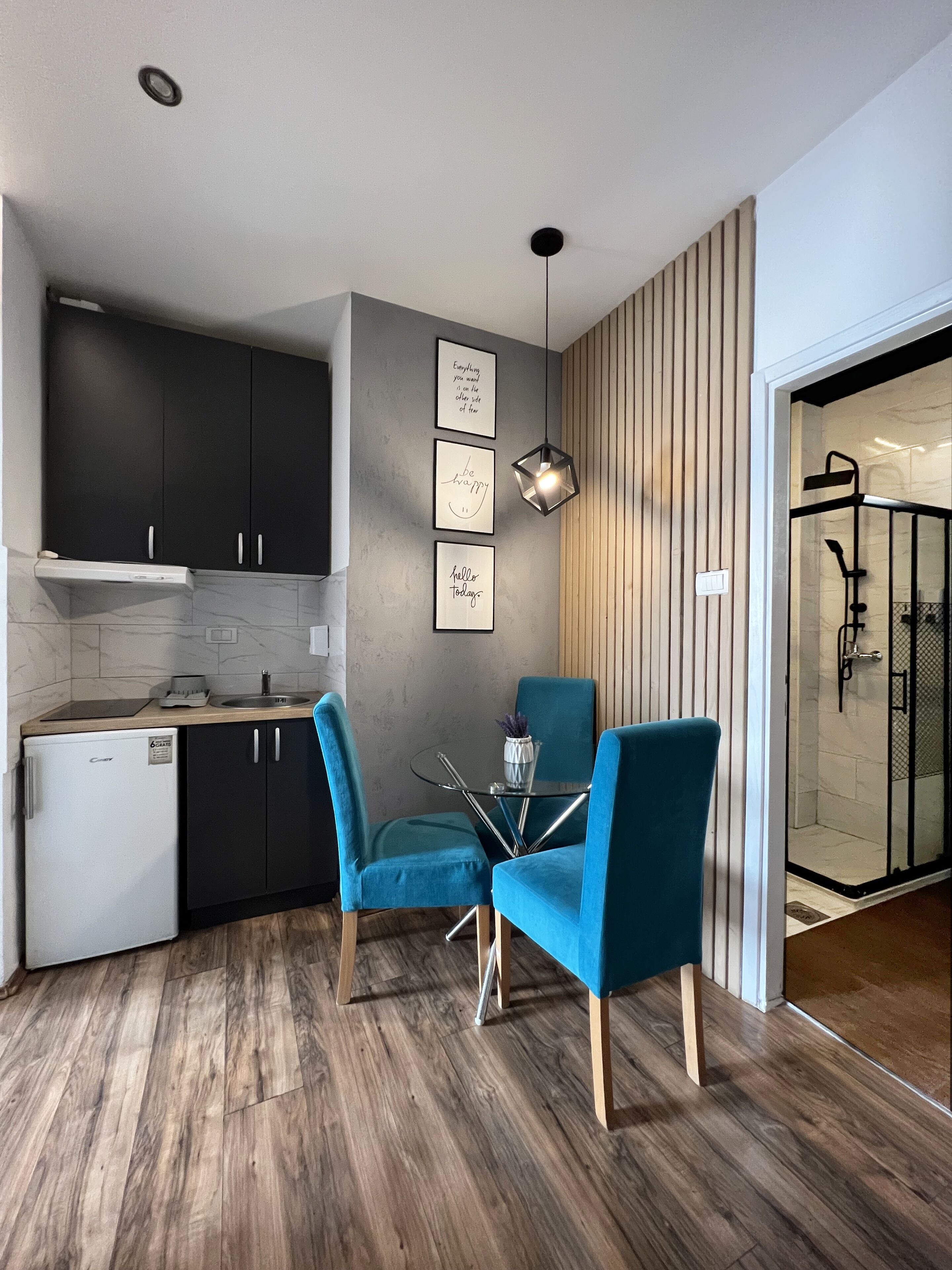 Una cocina moderna con armarios oscuros, un refrigerador blanco y una pequeña isla con una mesa de vidrio y sillas.