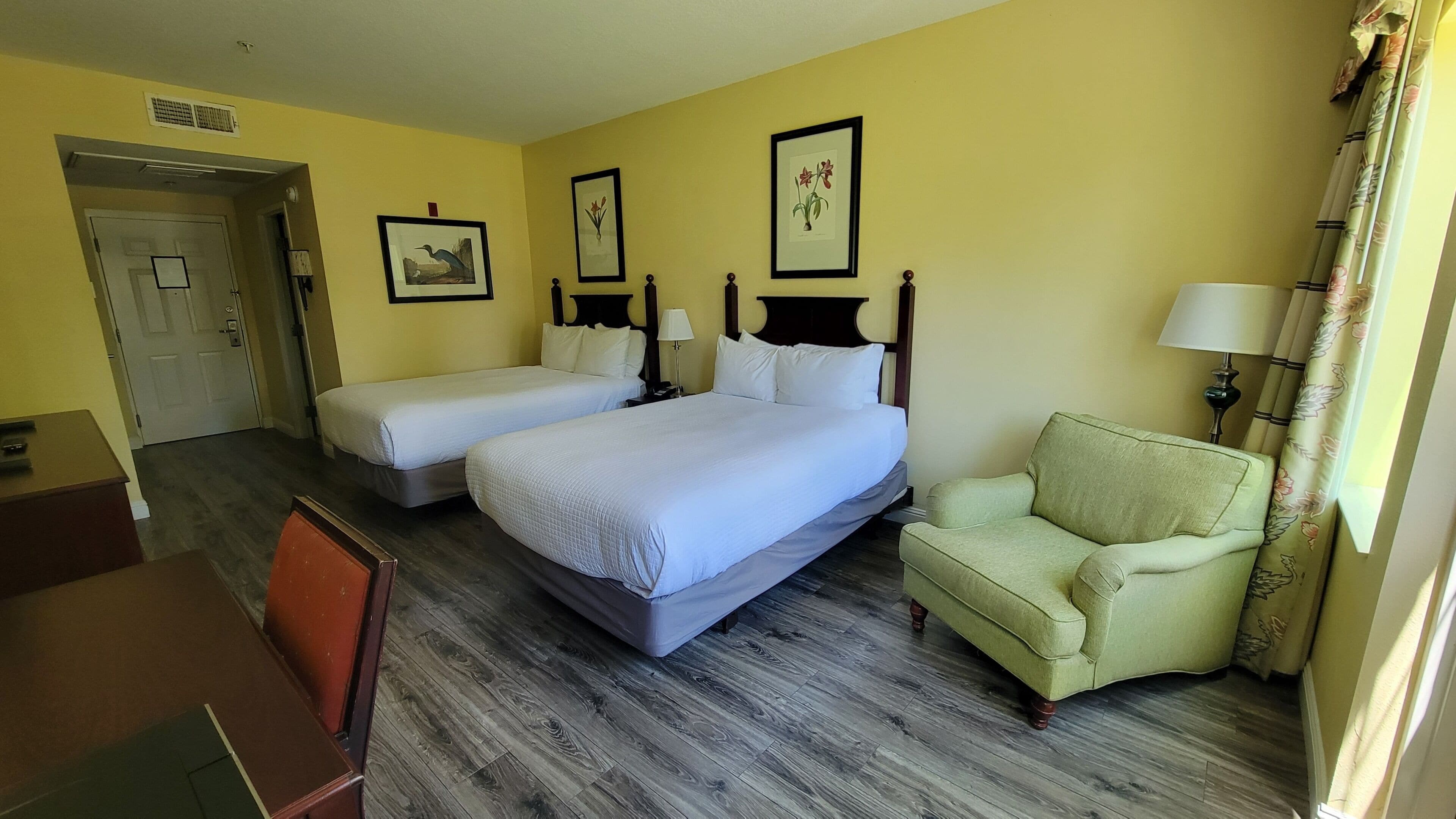 Een hotelkamer met twee bedden, een stoel, een bureau en een deur.