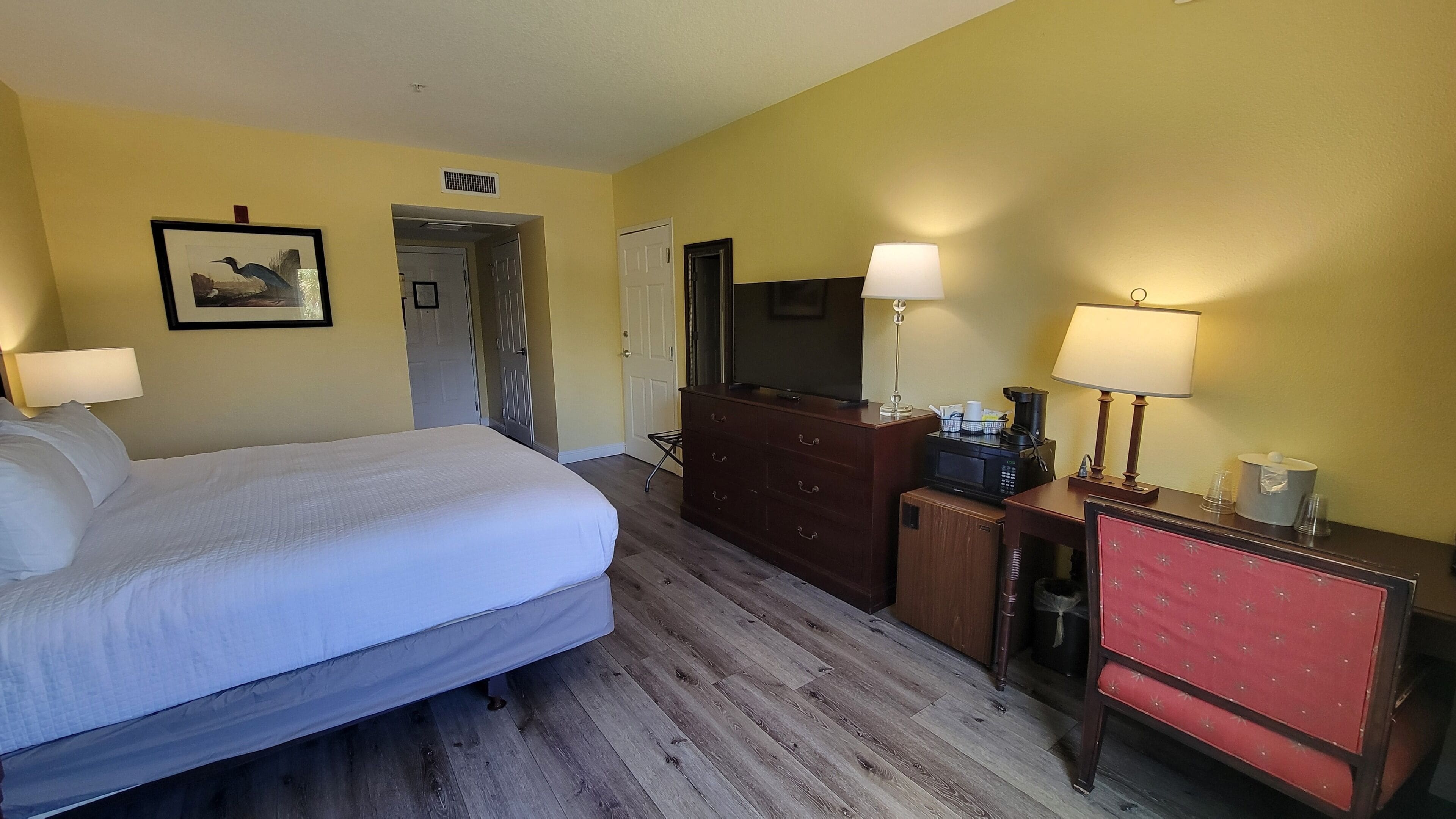 A hotel room with a bed, a dresser, a television, and two lamps.