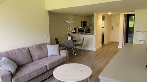 Ein modernes Wohnzimmer mit einer Couch, einem runden Couchtisch und einem Essbereich mit Stühlen und einem kleinen Tisch.