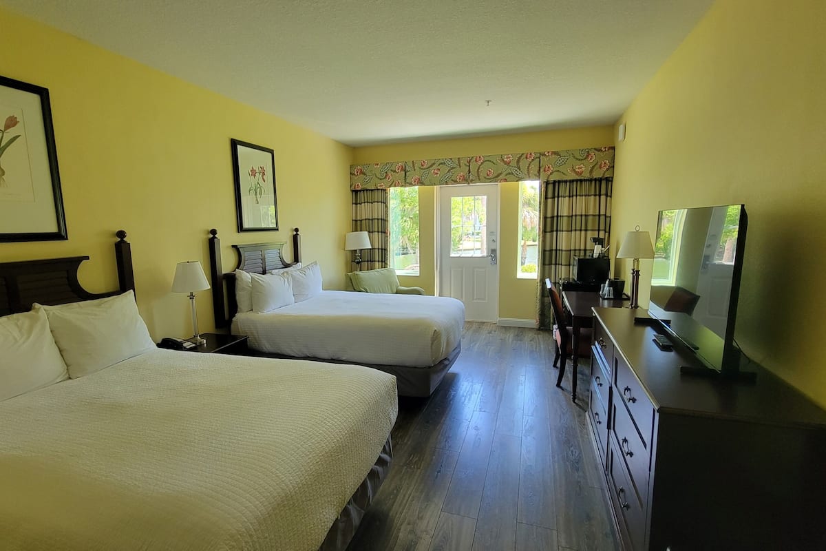 Habitación de hotel con dos camas, un televisor, un escritorio y una ventana con cortinas.