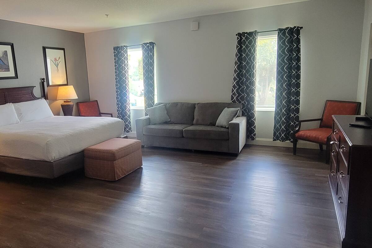 Una habitación de hotel con cama, sofá, sillón y escritorio.