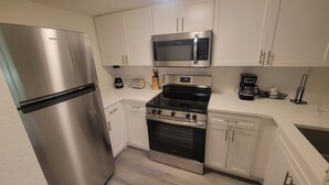 Una cocina moderna con electrodomésticos de acero inoxidable, incluyendo un refrigerador, microondas, estufa y horno.