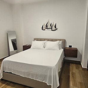 Un dormitorio con cama, mesita de noche, lámpara de pared y espejo.